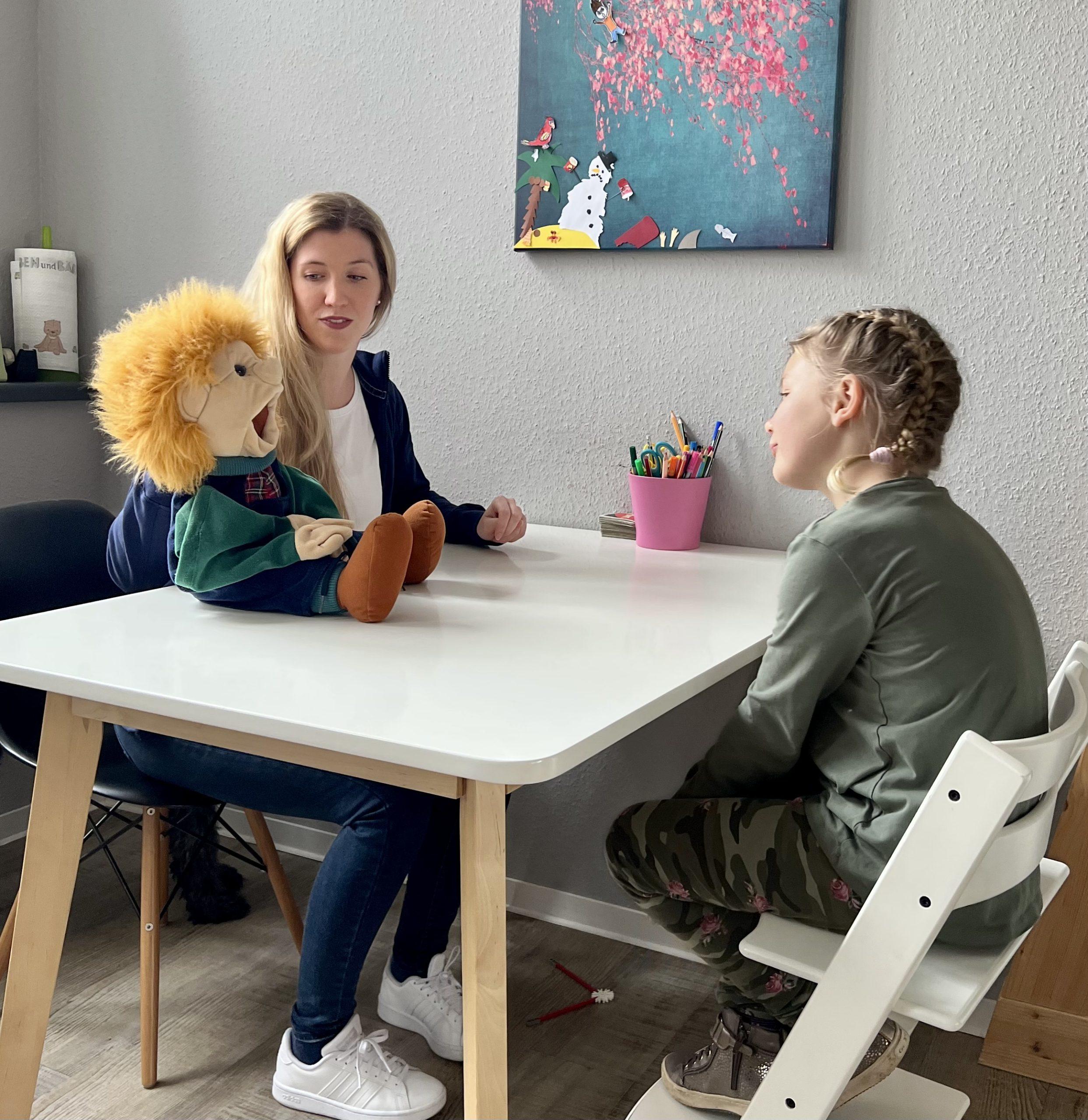 Eine Therapeutin setzt eine Handpuppe ein, um während einer Therapiesitzung beim Therapieteam Fimmers in Krefeld mit einem Kind zu interagieren.